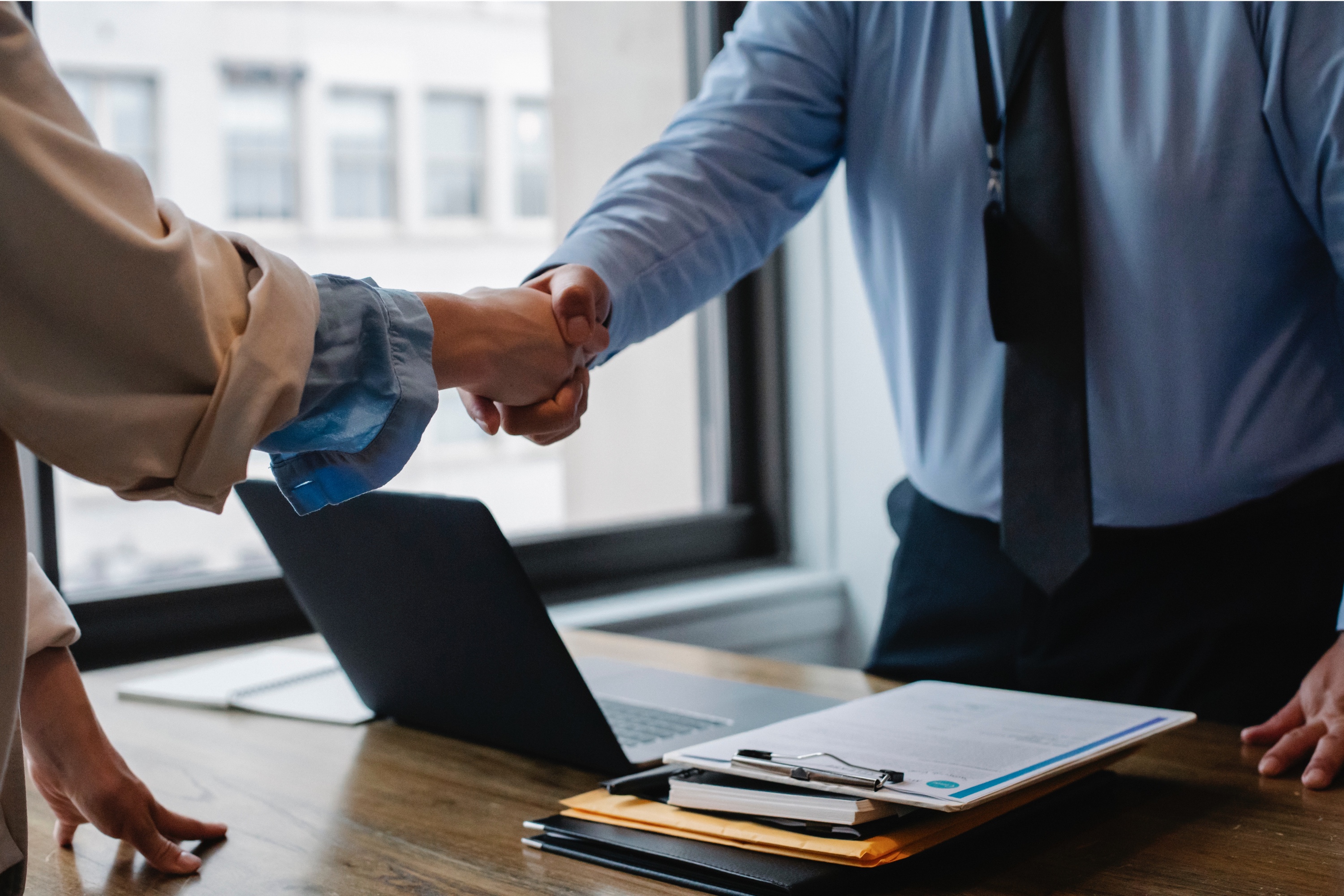 people shaking hands over a work desk
